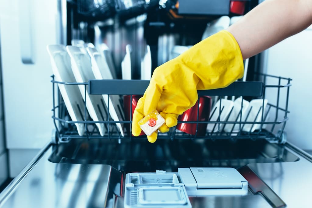 Person holding dishwasher tablet over dishwasher