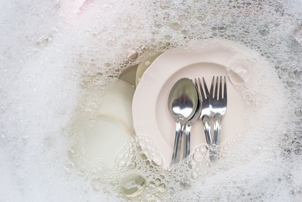 Silverware soaking in washing up liquid and water solution