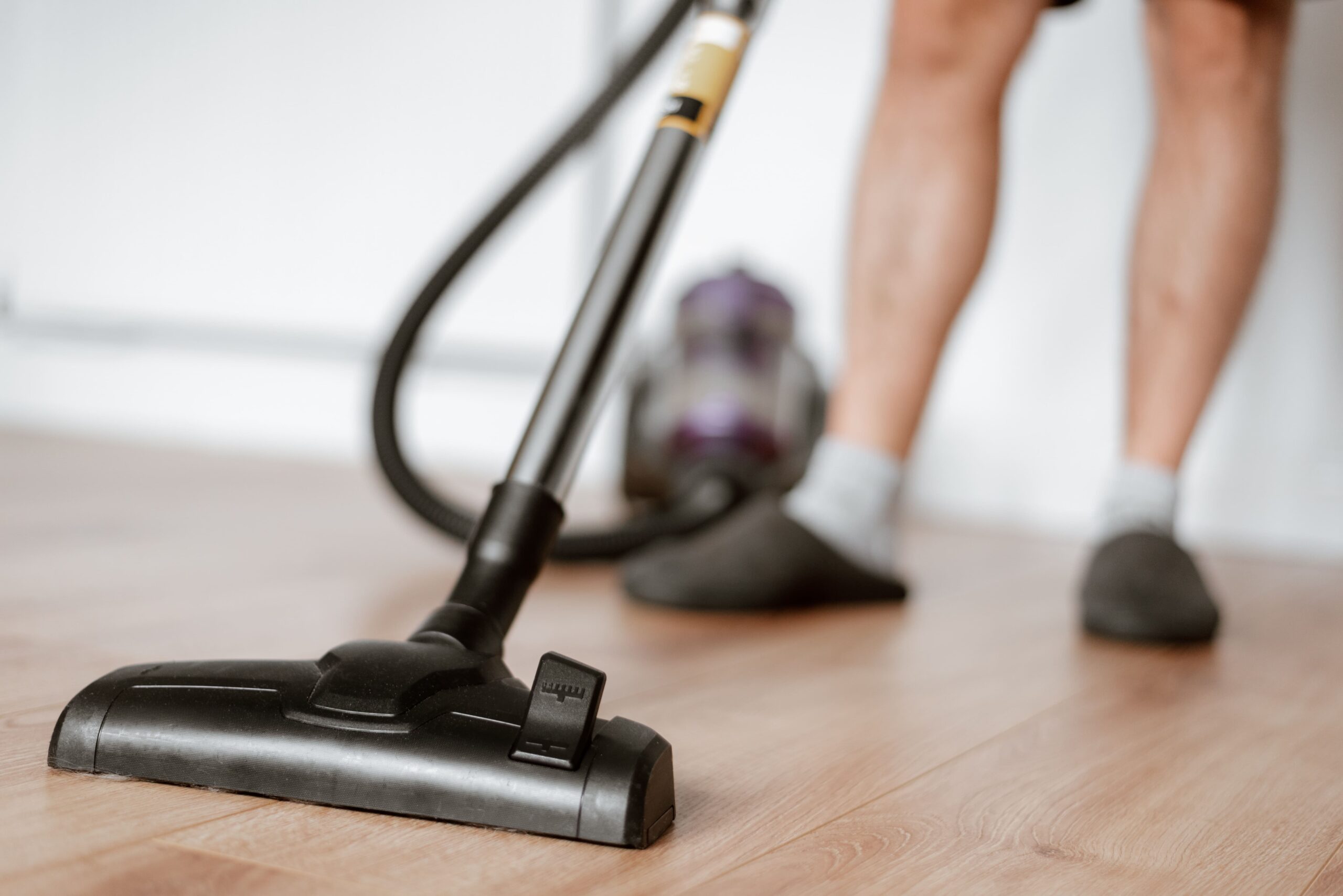 Une personne qui passe l'aspirateur sur du parquet