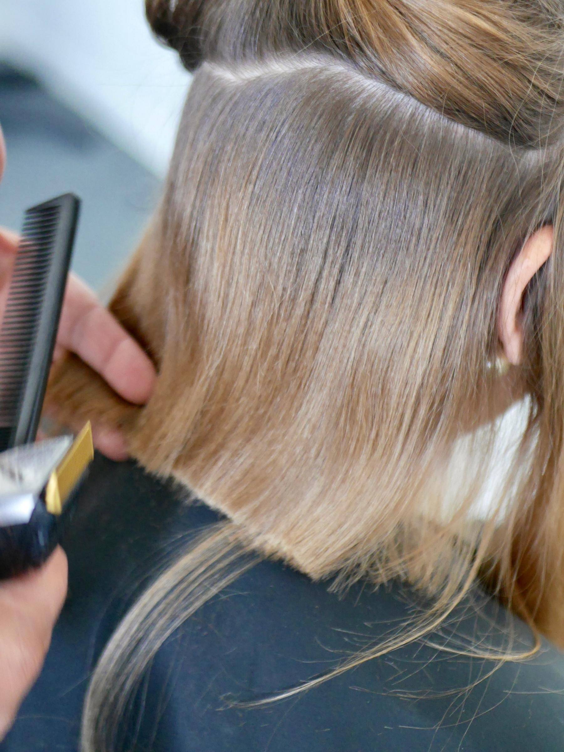 jeune femme se faisant couper les cheveux par sa coiffeuse à domicile