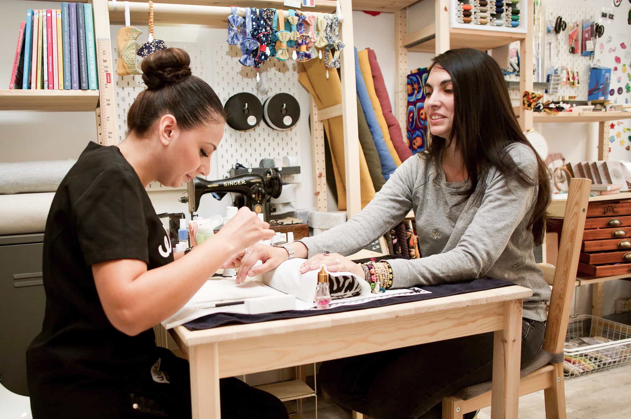Une prothésiste ongulaire travaille les ongles d'une femme.