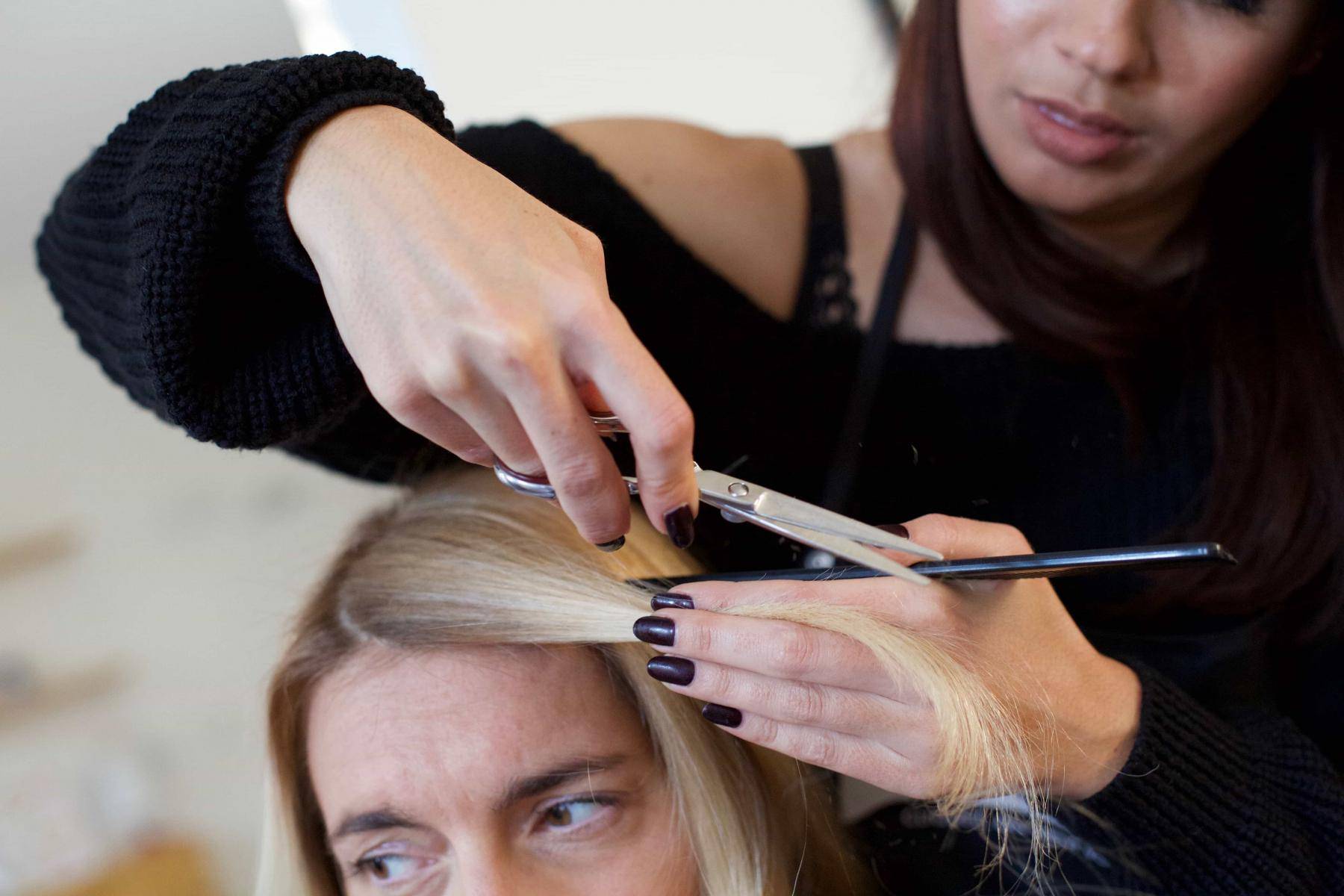 Une coiffeuse à domicile coupe les cheveux d'une femme