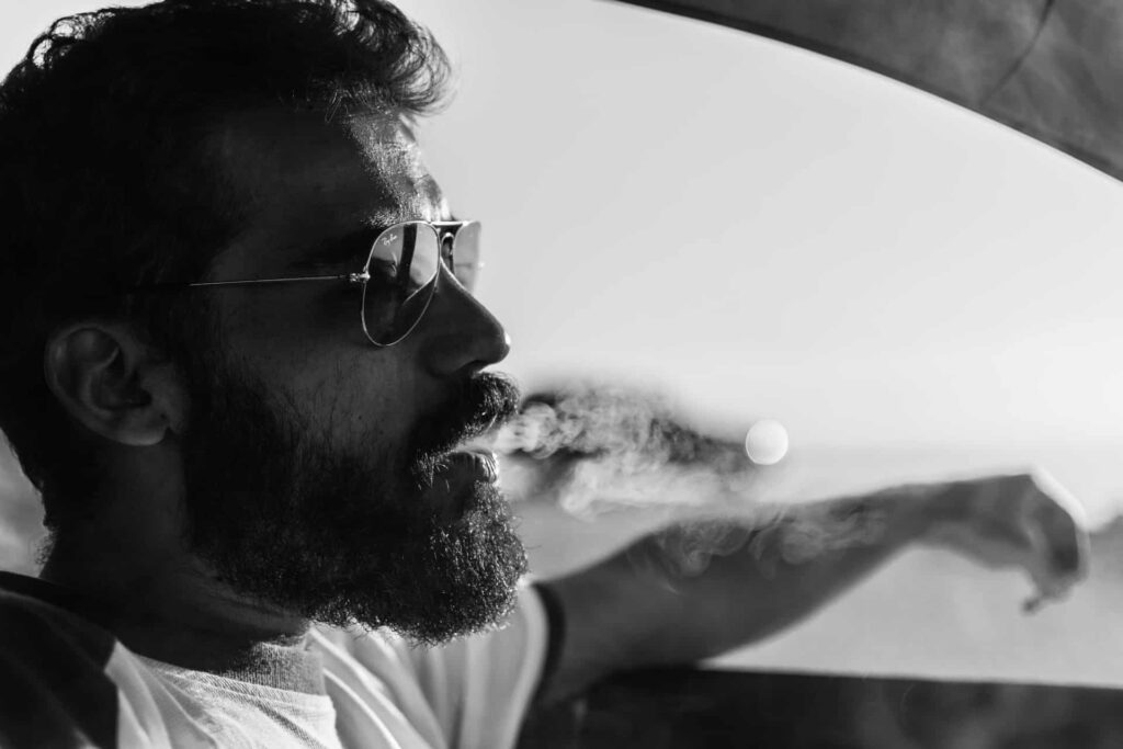 Homme en voiture avec une belle barbe fournie et des lunettes de soleil