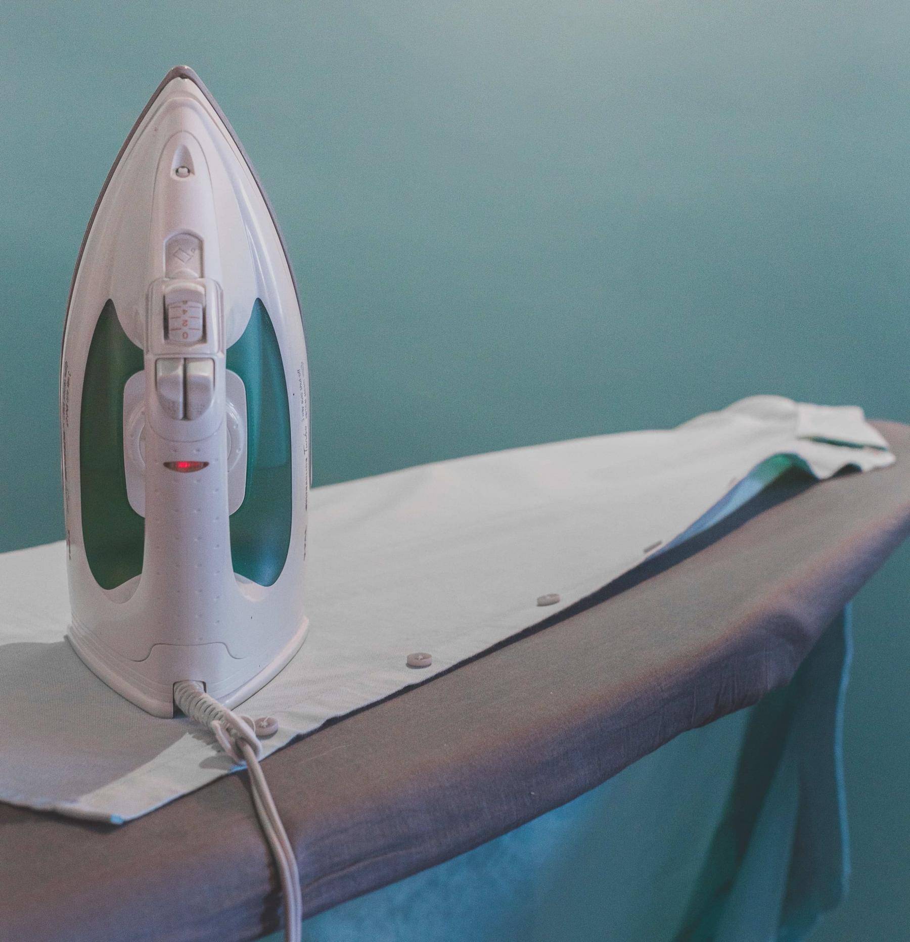 Une chemise en polyester est posée près d'un fer à repasser.