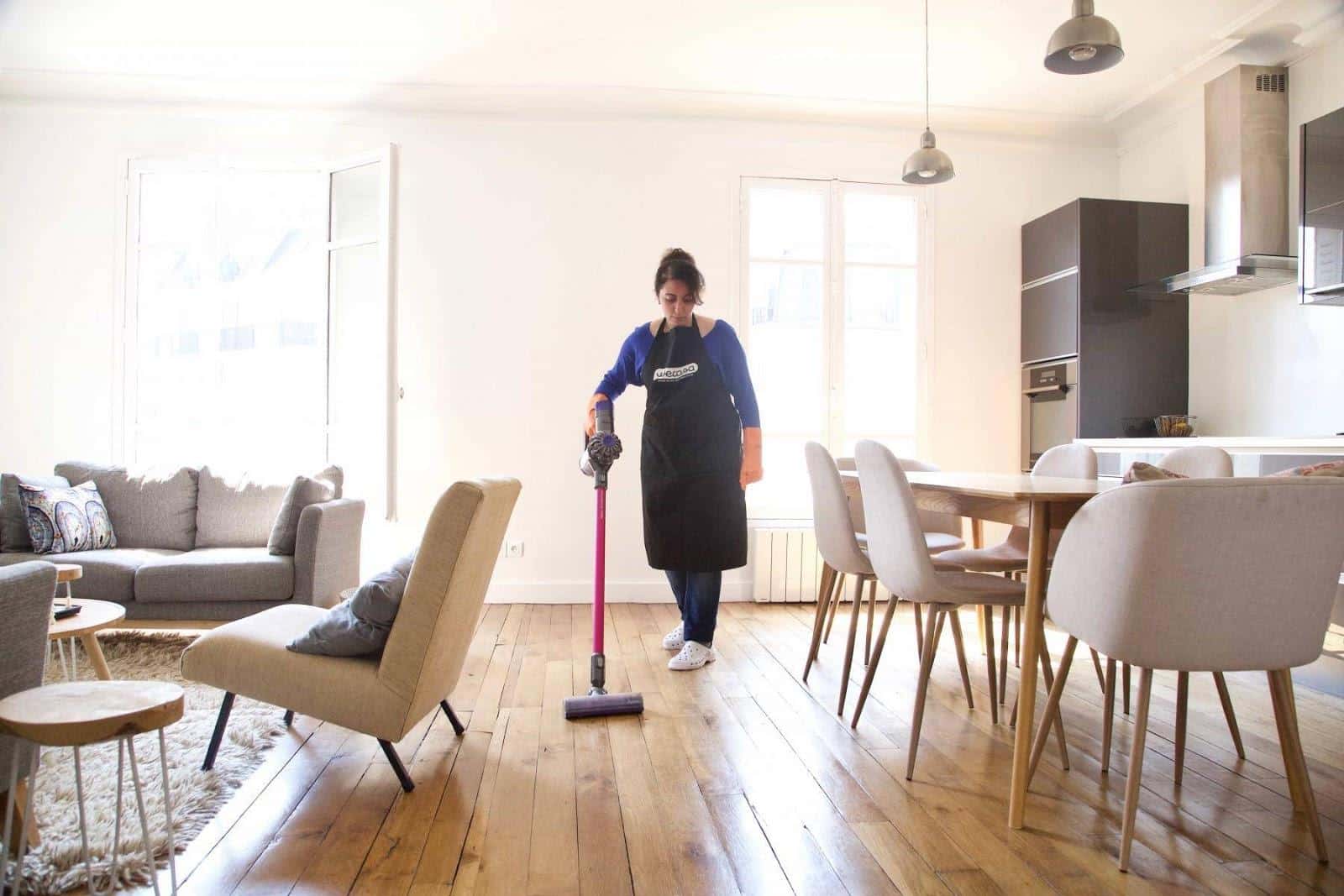 Une aide ménagère nettoie le parquet à l'aspirateur