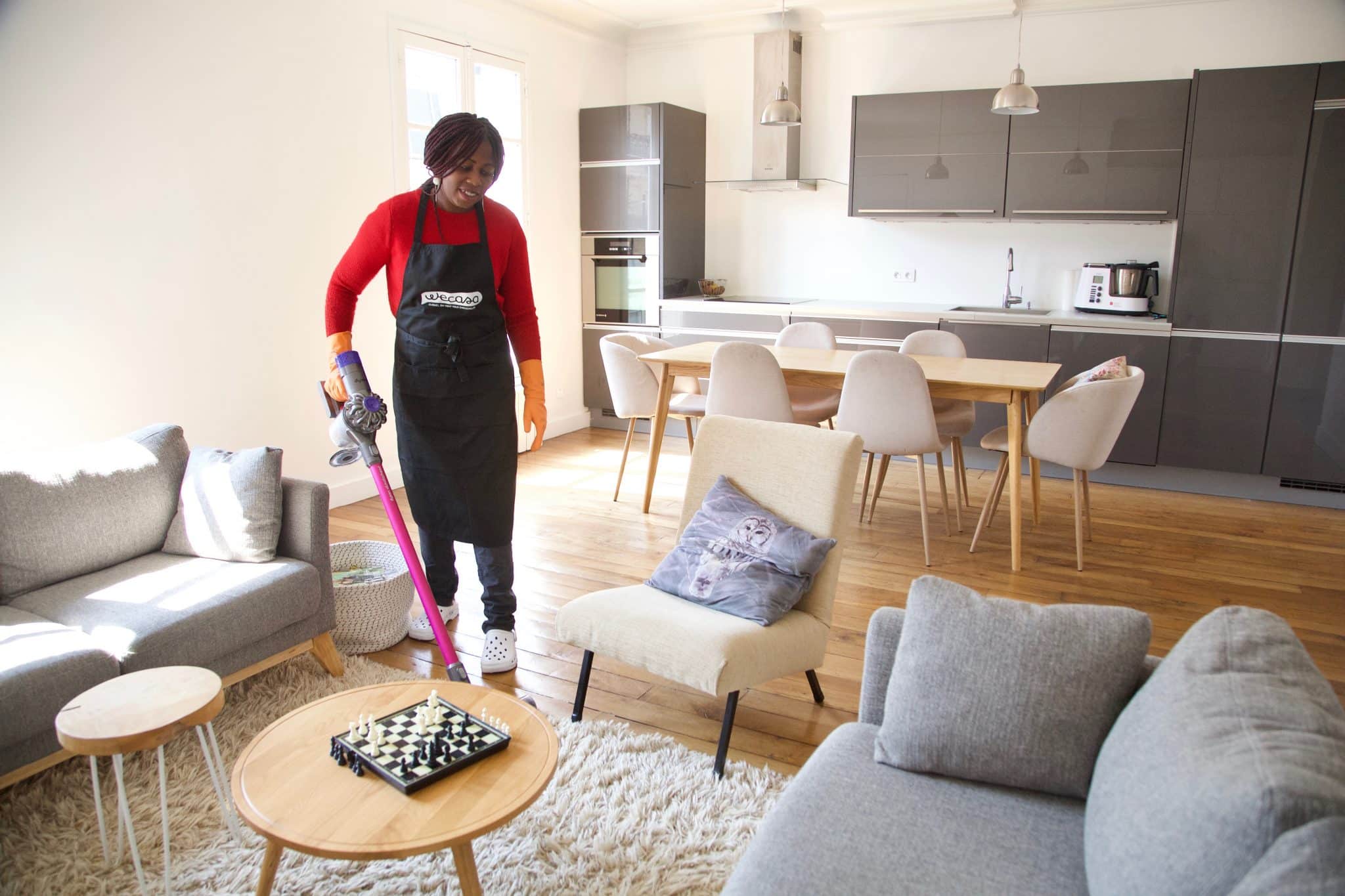 Femme de ménage auto-entrepreneur avec Wecasa passant l'aspirateur dans un salon