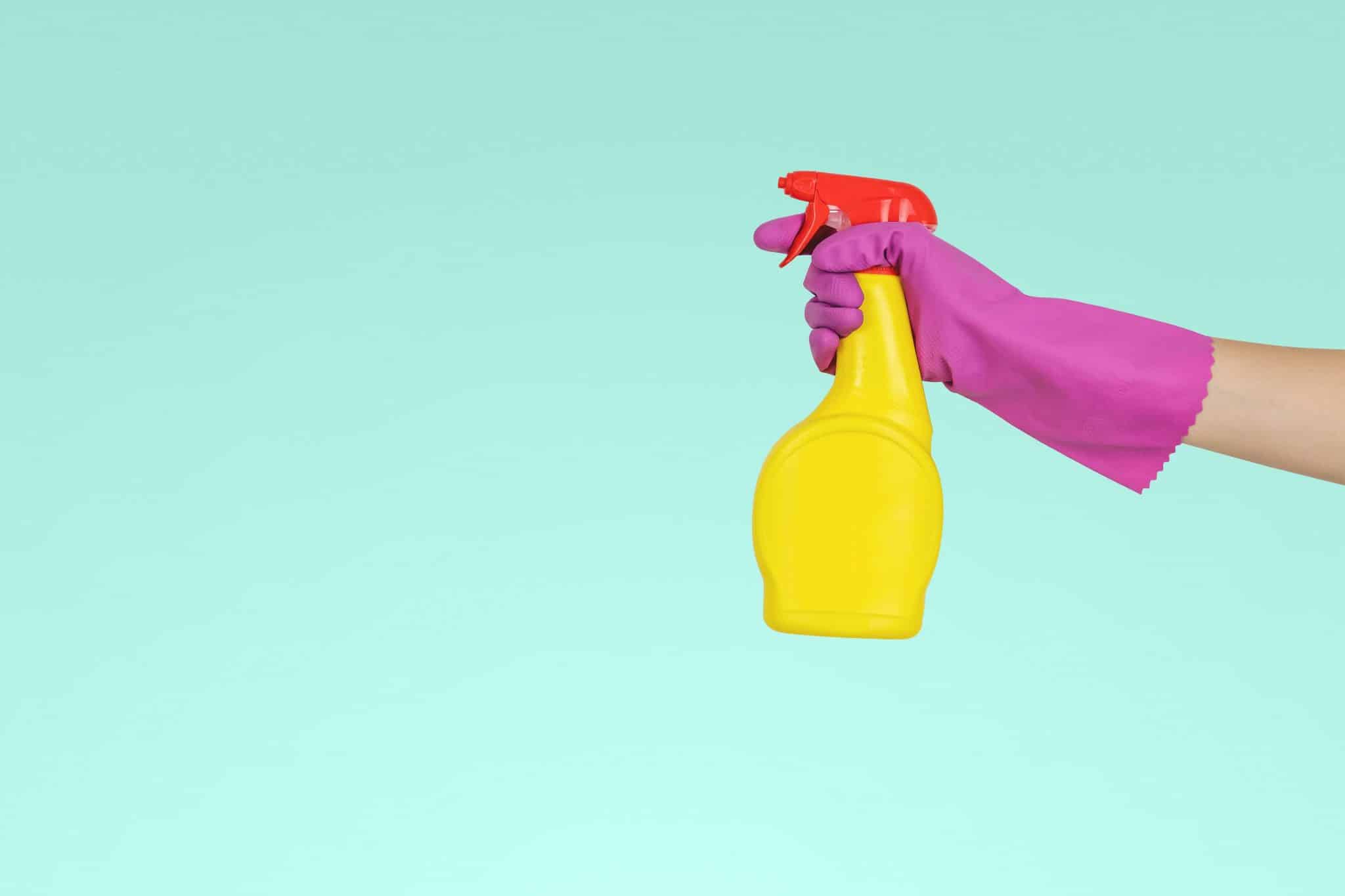 Une aide ménagère tenant un flacon de vinaigre.