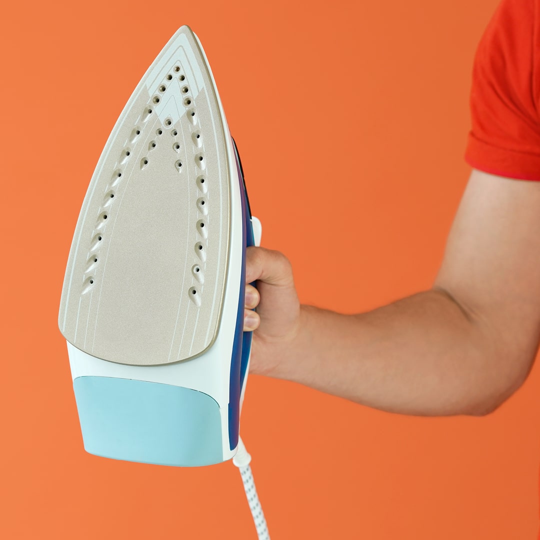 Aide ménagère à domicile tenant un fer à repasser