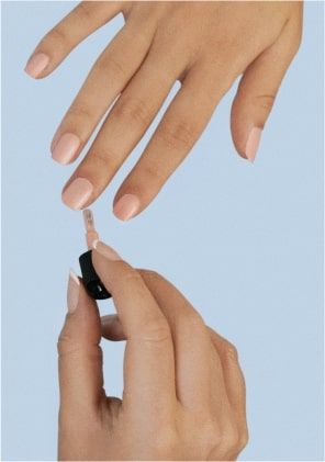 Une esthéticienne pose du vernis à ongles sur les mains d'une cliente